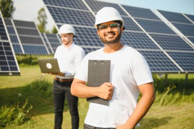 Güneş çiftliği, güneş paneli ve iki mühendis sistemin işleyişini kontrol etmek için yürür, dünyanın enerjisini korumak için alternatif enerji, temiz enerji üretimi için fotovoltaik modül fikri