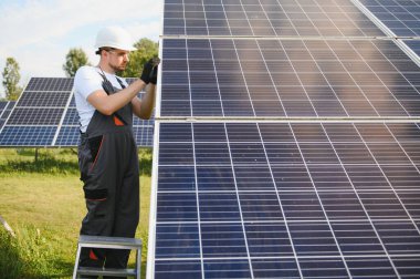 Fotovoltaik güneş modülleri monte eden adam teknisyen. Miğferdeki mühendis dışarıda güneş paneli kuruyor..