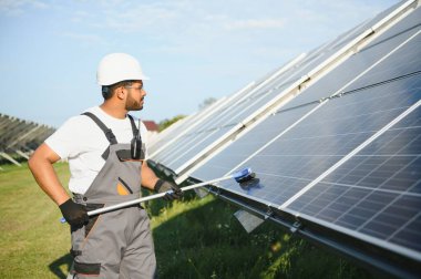 Genç bir Hintli temizlikçi güneş panellerini temizliyor..