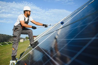 Profesyonel Hintli işçi güneş panellerini fırça ve yeşil elektrik teknolojisiyle temizliyor..