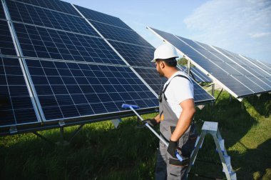 Genç bir Hintli temizlikçi güneş panellerini temizliyor..