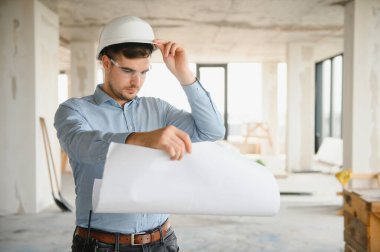 Planı ellerindeyken. Üniformalı adam inşaat alanında çalışıyor..