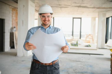 Planı ellerindeyken. Üniformalı adam inşaat alanında çalışıyor..