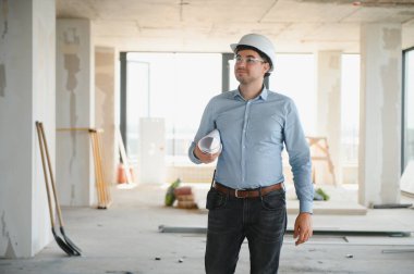 Planı ellerindeyken. Üniformalı adam inşaat alanında çalışıyor..