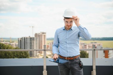 İnsan üreticisi. İnşaat alanında mimar. Tablet bilgisayarı ve kağıtları olan bir inşaatçı. Adam müfettişi inşaat kalitesini kontrol ediyor. İnşaat halindeki çok katlı binanın yanındaki mühendis..