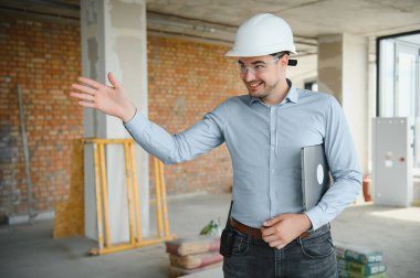 İnsan üreticisi. İnşaat alanında mimar. Tablet bilgisayarı ve kağıtları olan bir inşaatçı. Adam müfettişi inşaat kalitesini kontrol ediyor. İnşaat halindeki çok katlı binanın yanındaki mühendis..