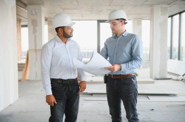 Hintli ve Avrupalı inşaat işçileri bir inşaat sahasında birlikte.