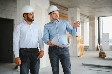 İki mimar mühendis inşa edilmiş bir ofis binasında yürüyorlar. Projenin uygulanması.