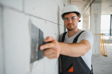 Üniformalı işçiler duvarları sıva ile kaplıyor..