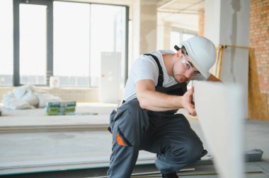 İnşaat alanında çalışırken kasketli yakışıklı bir erkek müteahhit.