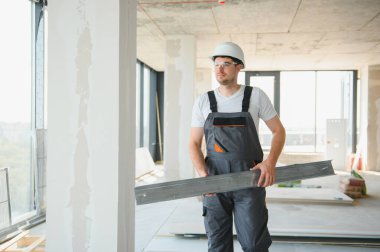 İnşaat alanındaki inşaat alanındaki kesme makinesiyle metal profili kesen çalışan bir inşaat işçisi.