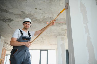 İnşaat alanında çalışırken kasketli yakışıklı bir erkek müteahhit.