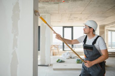 Boyacı duvarı boyuyor, boya silindiriyle..