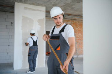 Duvarı boyayan ressamın yan görüntüsü, büyük boş alanda boya silindiri ile. Uzayı kopyala Pankart