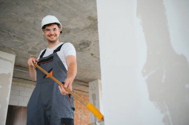 Boyacı duvarı boyuyor, boya silindiriyle..