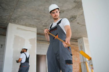 Duvarı boyayan ressamın yan görüntüsü, büyük boş alanda boya silindiri ile. Uzayı kopyala Pankart