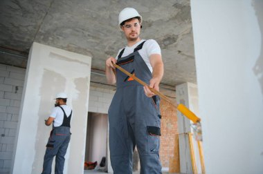 Duvarı boyayan ressamın yan görüntüsü, büyük boş alanda boya silindiri ile. Uzayı kopyala Pankart
