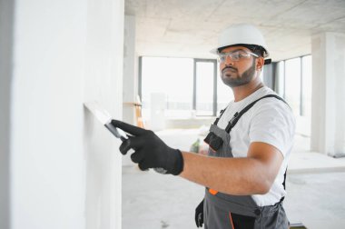 Profesyonel işçi duvarları macun bıçağıyla sıva yapıyor..