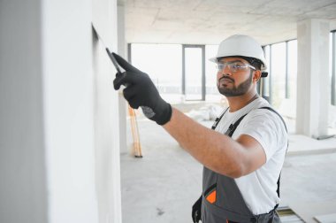 Profesyonel işçi duvarları macun bıçağıyla sıva yapıyor..