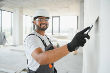 Profesyonel işçi duvarları macun bıçağıyla sıva yapıyor..