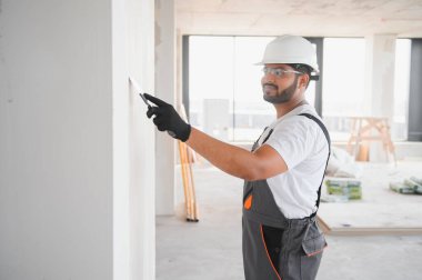 İş tulumlu erkek müteahhit inşaat malası kullanarak duvarı sıvamış..