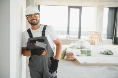 Profesyonel işçi duvarları macun bıçağıyla sıva yapıyor..