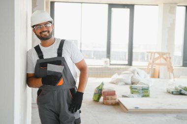 Profesyonel işçi duvarları macun bıçağıyla sıva yapıyor..