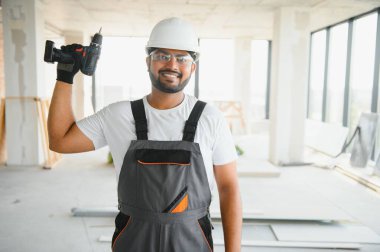 Üniformalı ve kasklı genç Hintli işçinin portresi. İnşaat ve onarım konsepti.