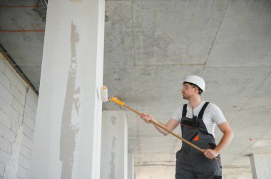 Boyacı duvarı boyuyor, boya silindiriyle..