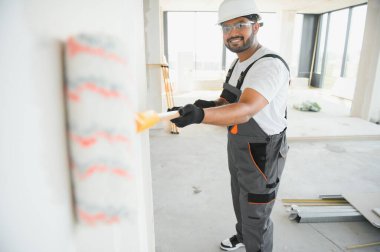 Ressam duvarda silindirle resim yapıyor. Çok çalışma, ev yenileme konsepti.