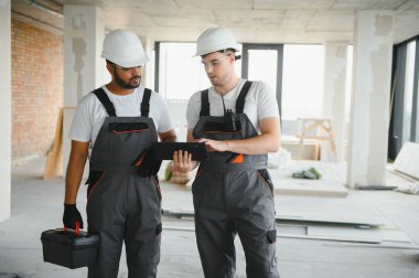 Hintli ve Avrupalı inşaat işçileri bir inşaat sahasında birlikte.