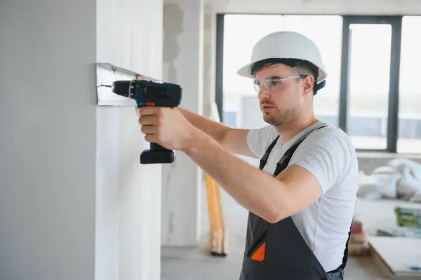 stock image Construction worker installing metal profile for interior partition wall, while building a new house or renovation process, viewed from his back