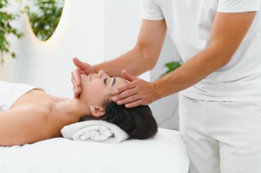 Güzel bir kadın güzellik salonunda yüz gerdirme masajından hoşlanıyor..