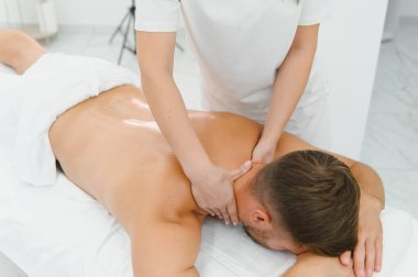 Genç bir adam profesyonel bir masöz tarafından masaj yaptırıyor..