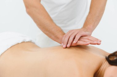 Modern bir kaplıcada profesyonel vücut masajından hoşlanan bir kadın. Yetenekli bir masör sırtına nazikçe masaj yaparken rahat genç bir bayan masaj masasında yatıyor. Güzellik, sağlık, zevk, konsept.