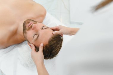 Stres önleyici baş masajı. Yakışıklı adam masaj salonunda kafa masajı yaparken rahatlıyor..