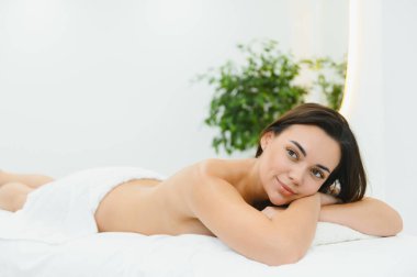 Masaj masasında uzanmış, güzellik salonunda keyif çatan, tasasız bir kadının portresi. Mutlu, rahat, güzel bayan, lüks içinde dinleniyor..