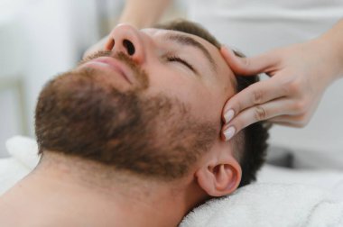 Kaplıca terapisti yakışıklı bir adam için rahatlatıcı bir masaj yapıyor. Erkek kozmetoloji kavramı.