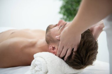 Stres önleyici baş masajı. Yakışıklı adam masaj salonunda kafa masajı yaparken rahatlıyor..