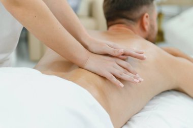 Genç bir adam profesyonel bir masöz tarafından masaj yaptırıyor..