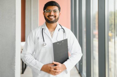 Steteskoplu beyaz önlüklü mutlu Hintli erkek doktor portresi. Tıbbi sağlık hizmeti kavramı.