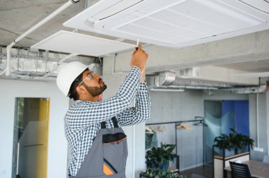 Yoğunlaşmış genç Hintli mühendis klima kuruyor..