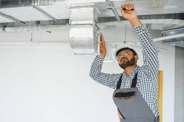 Hintli bir işçi ofis binasının havalandırma sistemini inceliyor..