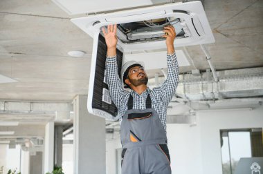 Yoğunlaşmış genç Hintli mühendis klima kuruyor..