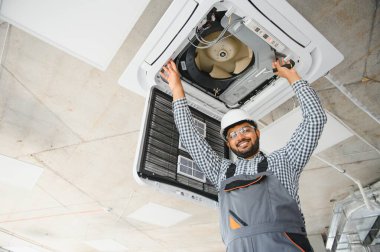 Yoğunlaşmış genç Hintli mühendis klima kuruyor..