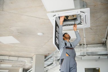 Yoğunlaşmış genç Hintli mühendis klima kuruyor..