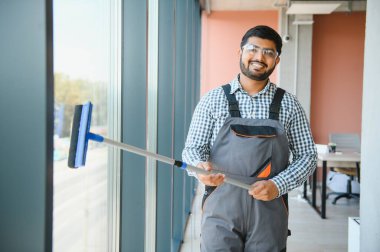 Bir Hintli temizlikçi ofis binasının camlarını siler..
