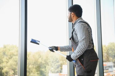Bir Hintli temizlikçi ofis binasının camlarını siler..
