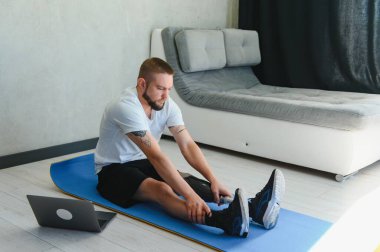 Protez bacaklı bir adam evdeki paspasın üstünde spor egzersizleri yapıyor. Rehabilitasyon kavramı.