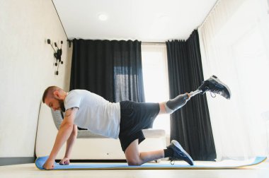 Uyluk kemiği protezinde protez bacak sakatlığı olan bir adam evde germe egzersizi yapan yapay bir cihaz kullanıyor. İnsanlar günlük yaşamlarında engelli oluyor..